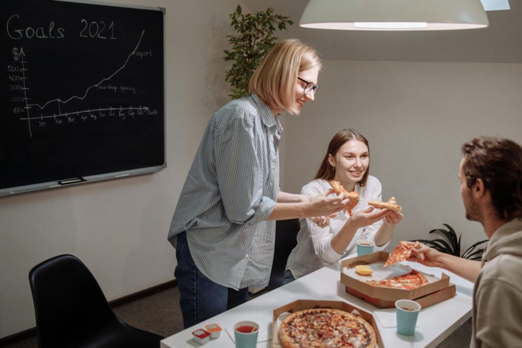A group of people eating pizza in the office